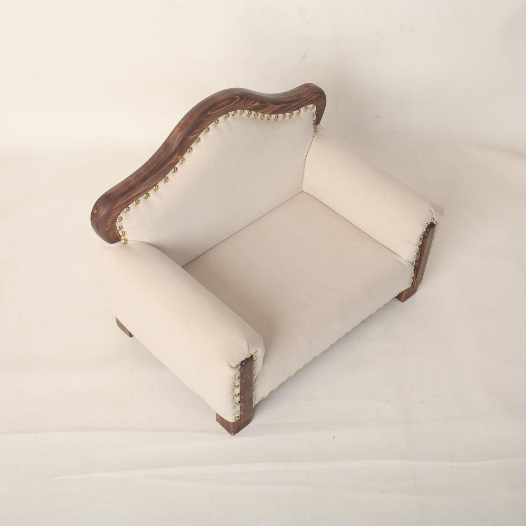 A sleek and elegant wooden sofa baby prop, designed for newborn and sitter photoshoots, offering a stylish and comfortable seating option for capturing timeless baby portraits.